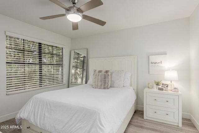 bedroom with light wood finished floors, baseboards, and a ceiling fan