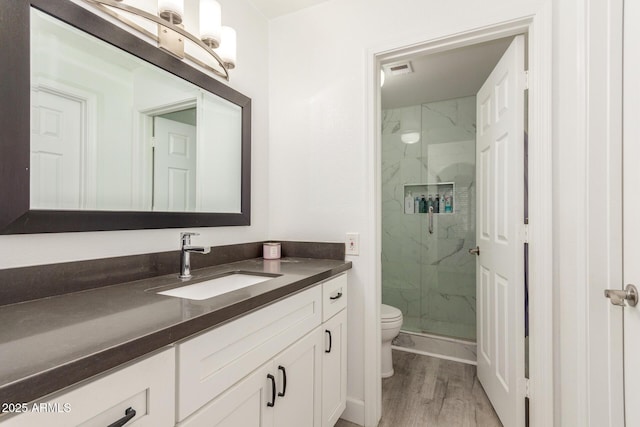 full bathroom with toilet, wood finished floors, visible vents, vanity, and a marble finish shower