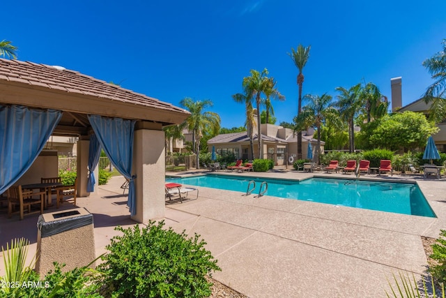 community pool with a patio, a gazebo, and fence