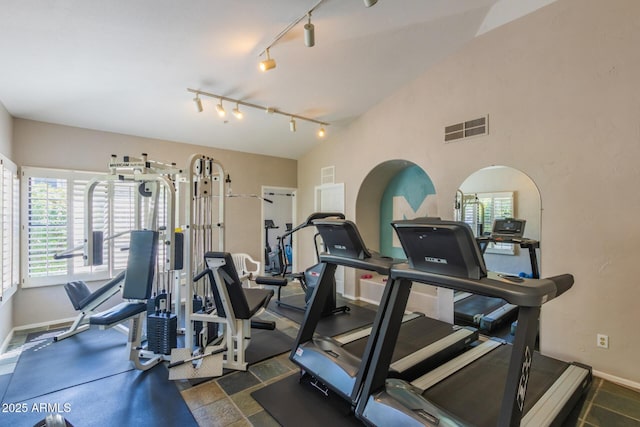 gym featuring vaulted ceiling, rail lighting, visible vents, and baseboards