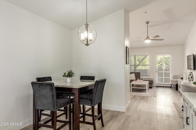 dining room featuring light wood-type flooring, lofted ceiling, baseboards, and ceiling fan with notable chandelier