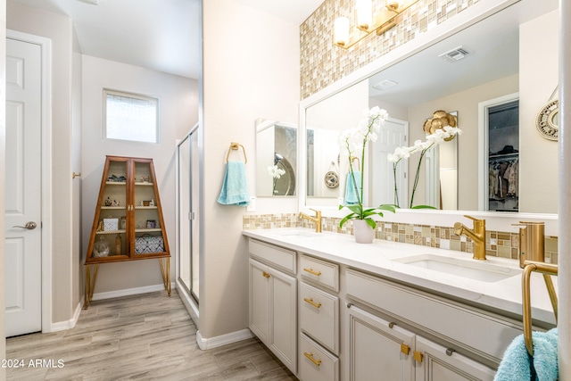 bathroom with decorative backsplash, wood-type flooring, a shower with shower door, and vanity