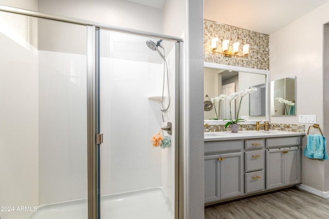 bathroom featuring decorative backsplash, vanity, wood-type flooring, and walk in shower