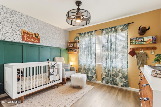 bedroom featuring a nursery area and light hardwood / wood-style floors