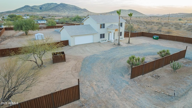 exterior space featuring an attached garage, fence private yard, a mountain view, driveway, and stucco siding