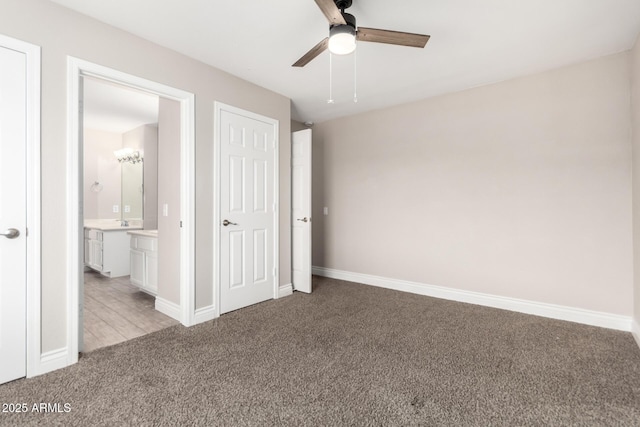 unfurnished bedroom featuring light carpet, ensuite bath, baseboards, and ceiling fan