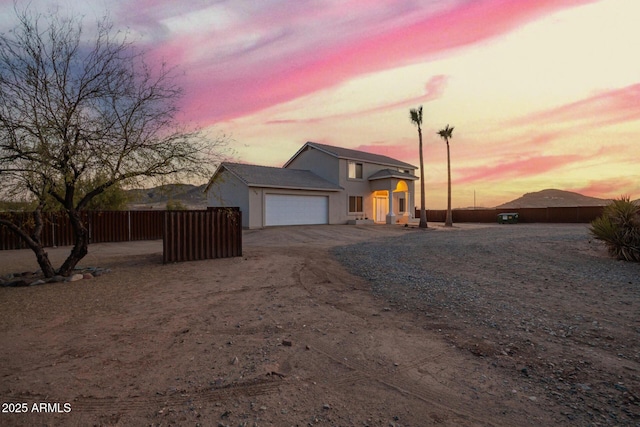 view of front of house featuring an attached garage, driveway, fence, and stucco siding