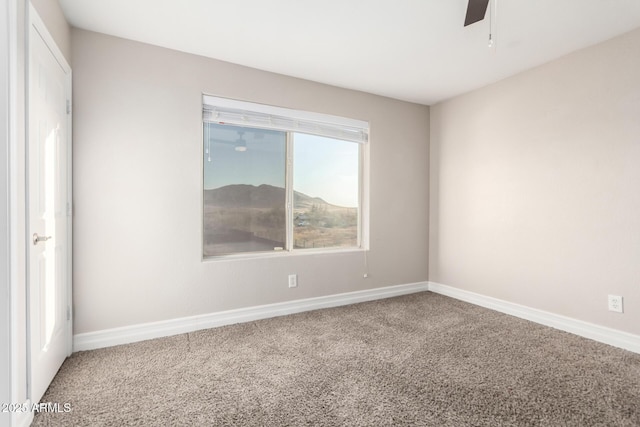 carpeted spare room featuring ceiling fan and baseboards