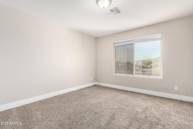 unfurnished room with carpet floors, visible vents, and baseboards