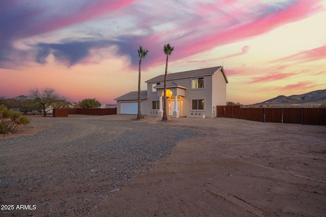 view of front of house featuring driveway, an attached garage, fence, and stucco siding