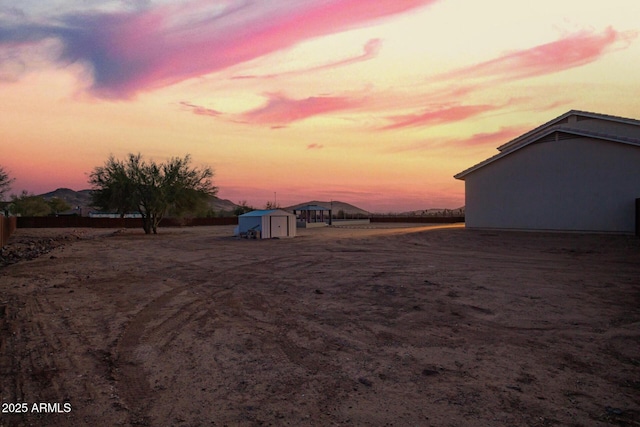 yard at dusk featuring an outbuilding and a shed