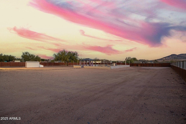 yard at dusk featuring a gazebo and fence