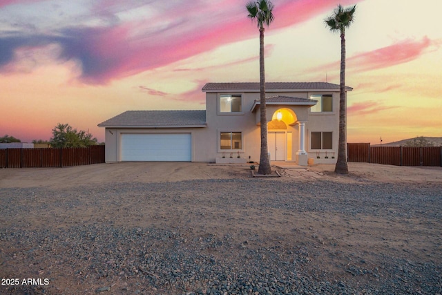 view of front of property featuring an attached garage, driveway, fence, and stucco siding