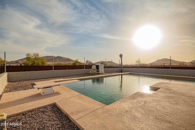 view of pool with a fenced in pool, a patio, a fenced backyard, a mountain view, and a diving board