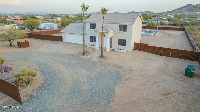 view of front of property with driveway, fence, a mountain view, and stucco siding