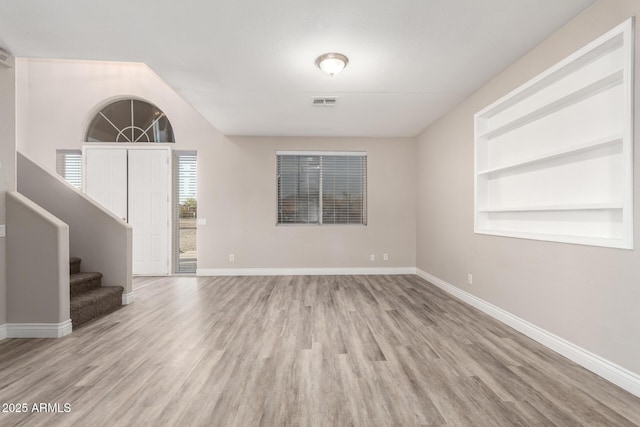 foyer with stairs, wood finished floors, visible vents, and baseboards