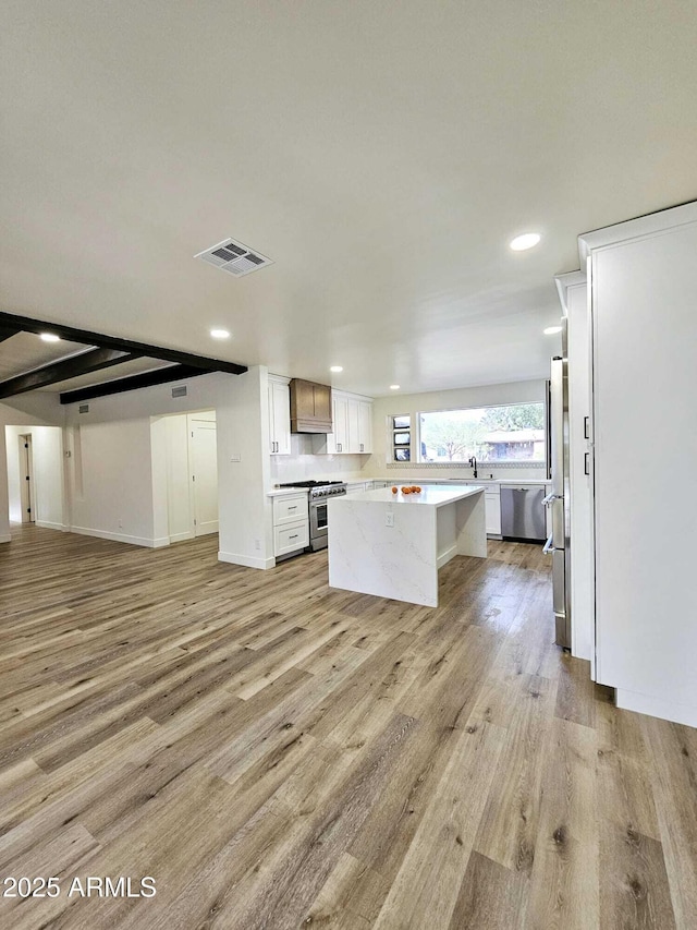 kitchen featuring light countertops, visible vents, light wood-style floors, open floor plan, and a kitchen island