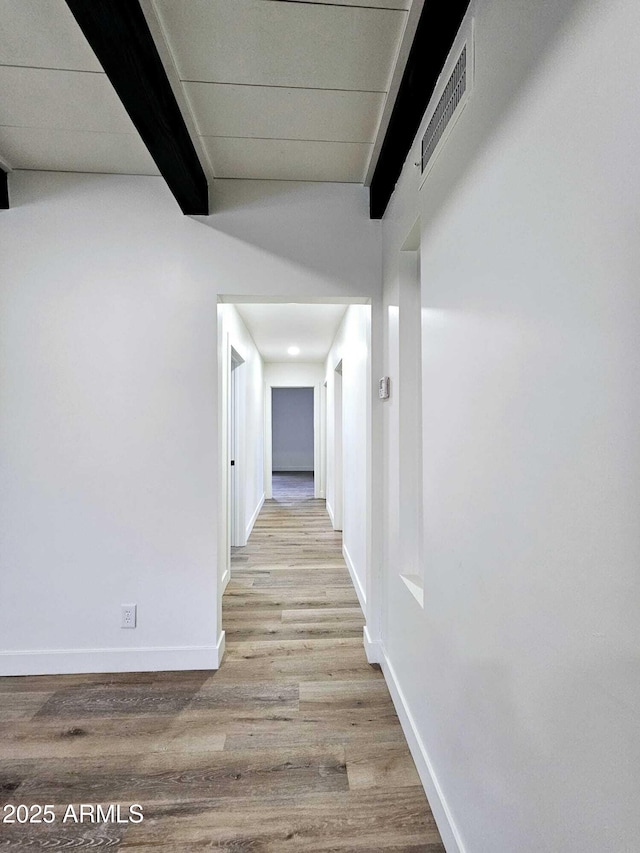 corridor with beam ceiling, visible vents, baseboards, and wood finished floors