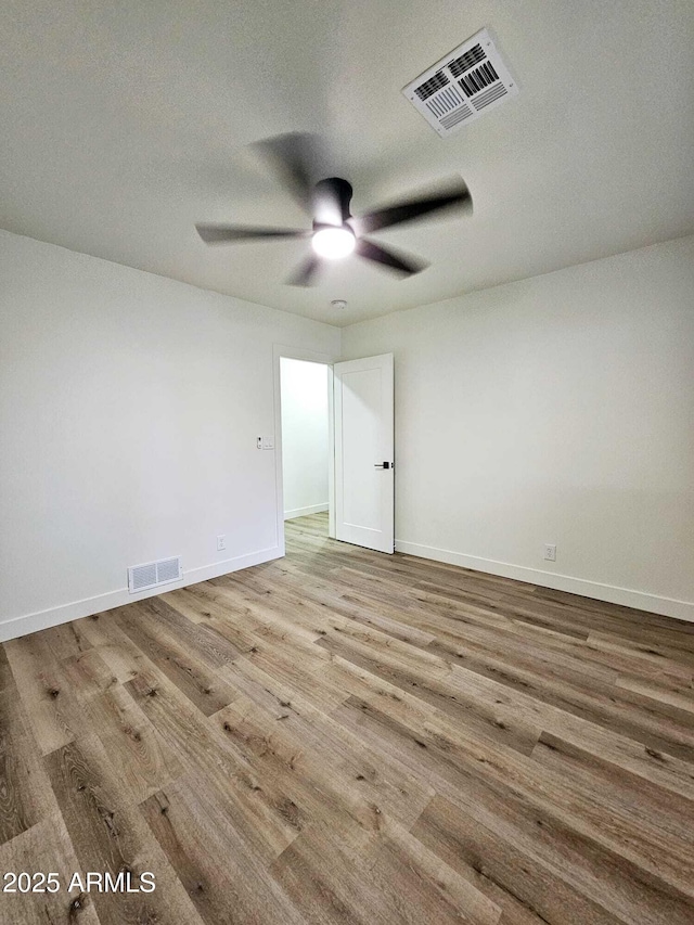 unfurnished room featuring a ceiling fan, visible vents, and wood finished floors