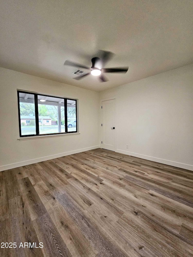 spare room featuring baseboards, visible vents, a ceiling fan, wood finished floors, and a textured ceiling