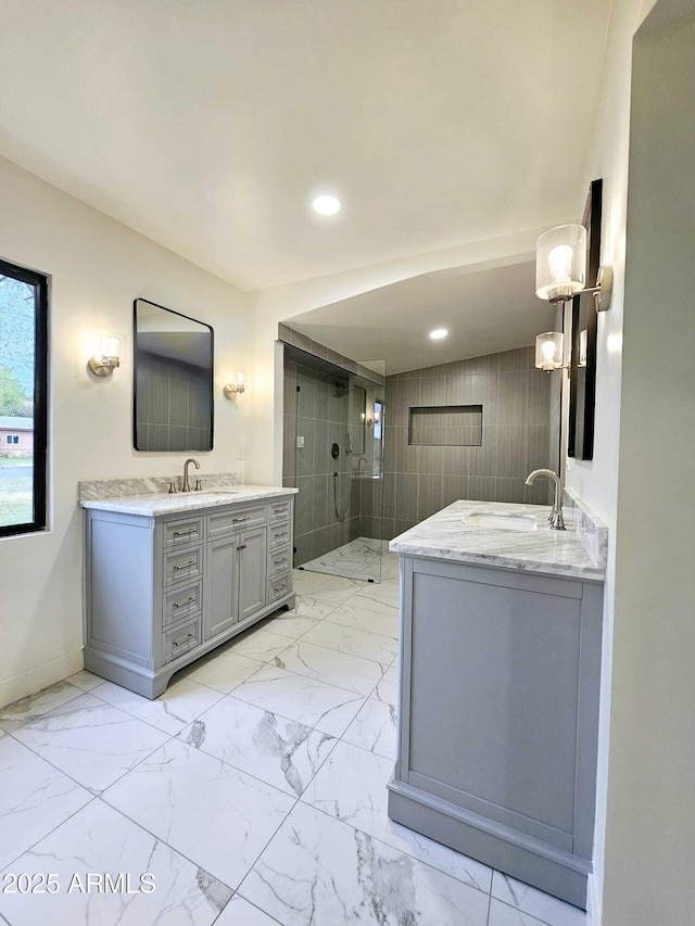 full bathroom featuring marble finish floor, two vanities, a sink, and a shower stall