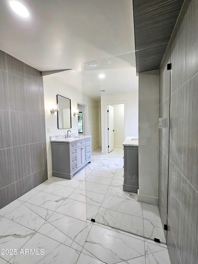 full bath with tile walls, marble finish floor, and vanity