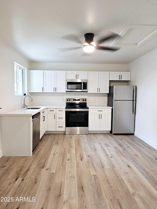 kitchen with stainless steel appliances, light countertops, a sink, and light wood finished floors