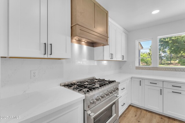 2425 E Harvard St, Phoenix, AZ 85008 - kitchen with recessed lighting, backsplash, high end stainless steel range oven, light wood-type flooring, and white cabinetry