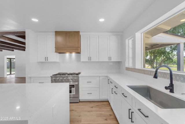 2425 E Harvard St, Phoenix, AZ 85008 - kitchen featuring white cabinets, light countertops, a sink, high end range, and custom range hood