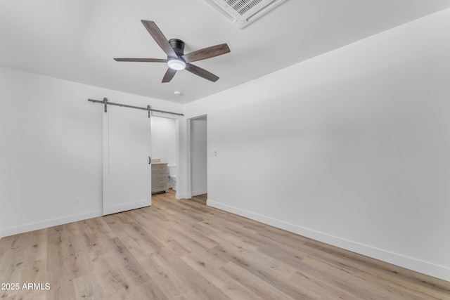 2425 E Harvard St, Phoenix, AZ 85008 - unfurnished bedroom with a barn door, light wood-type flooring, baseboards, visible vents, and ceiling fan