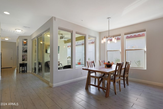 dining space with hardwood / wood-style flooring and ceiling fan with notable chandelier