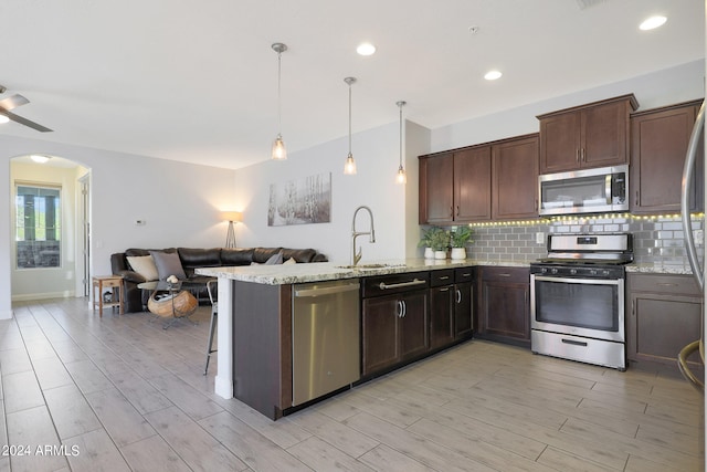 kitchen featuring pendant lighting, light hardwood / wood-style flooring, kitchen peninsula, and stainless steel appliances