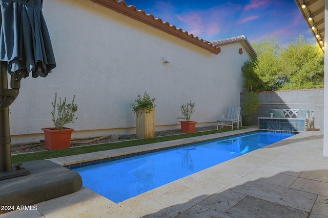 pool at dusk with a patio area