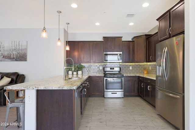 kitchen with decorative backsplash, stainless steel appliances, a breakfast bar, pendant lighting, and light stone counters