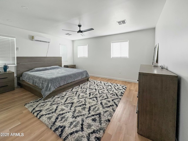 bedroom featuring ceiling fan, light wood-type flooring, and a wall mounted AC