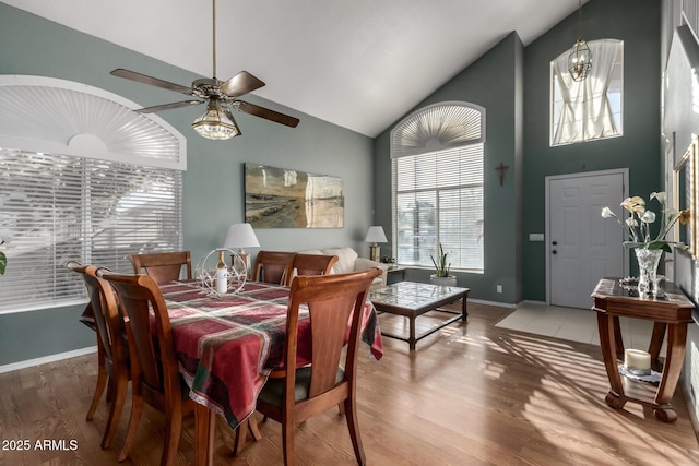 dining room featuring wood-type flooring, high vaulted ceiling, and ceiling fan