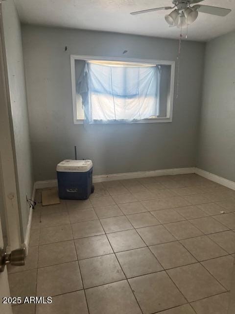 spare room featuring a ceiling fan, light tile patterned floors, and baseboards