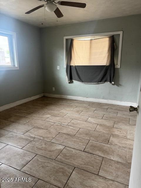 empty room with a ceiling fan and baseboards