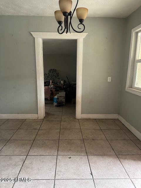 unfurnished dining area featuring light tile patterned floors, a chandelier, and baseboards