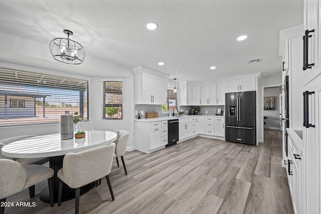 kitchen featuring appliances with stainless steel finishes, decorative light fixtures, white cabinetry, and light hardwood / wood-style floors