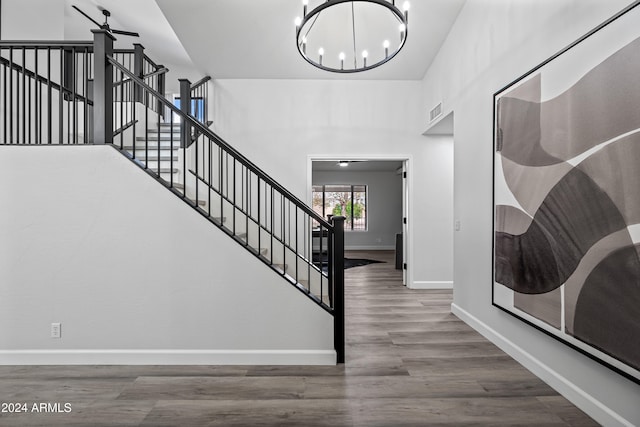 stairs with hardwood / wood-style floors and ceiling fan with notable chandelier