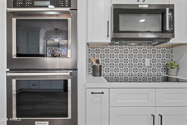 kitchen with decorative backsplash, appliances with stainless steel finishes, white cabinetry, and light stone counters