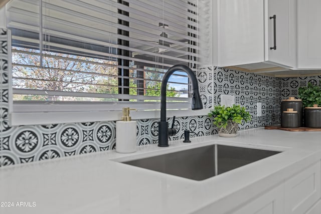 room details with white cabinetry, decorative backsplash, and sink