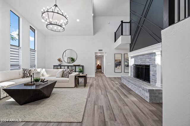 394 E Redfield Rd, Chandler, AZ 85225 - living room featuring wood finished floors, a towering ceiling, a chandelier, a brick fireplace, and baseboards