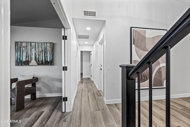 corridor featuring wood-type flooring and vaulted ceiling