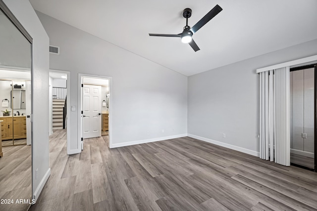 unfurnished bedroom featuring ensuite bathroom, ceiling fan, high vaulted ceiling, and light hardwood / wood-style flooring