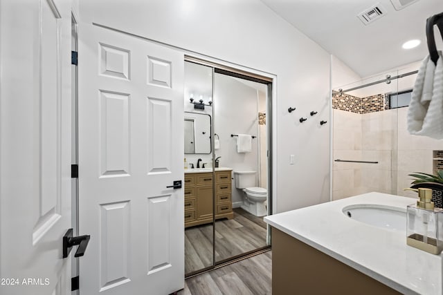 bathroom with walk in shower, vanity, wood-type flooring, and toilet