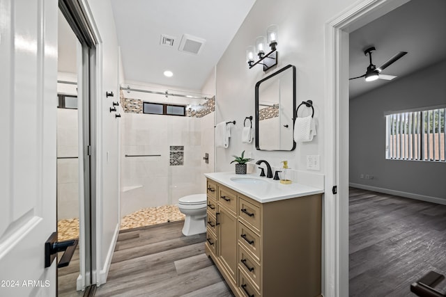 bathroom with ceiling fan, tiled shower, hardwood / wood-style floors, toilet, and lofted ceiling