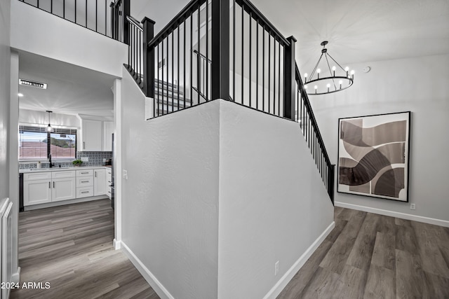 stairway featuring sink, wood-type flooring, and a notable chandelier