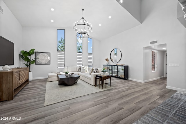 living room featuring light hardwood / wood-style floors, high vaulted ceiling, and a chandelier